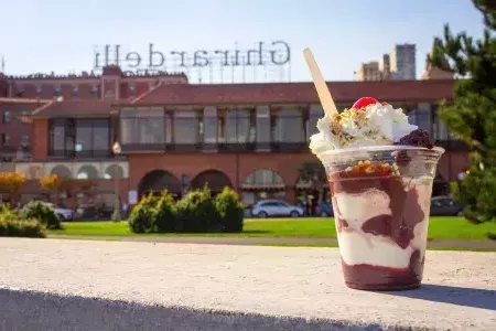 Im Vordergrund steht ein Schokoladenbecher, im Hintergrund der Ghirardelli Square.